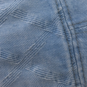Macro shot of light blue denim fabric with gray double stitching and twill weave detail