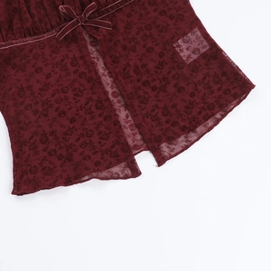 Detail of burgundy lace top with rose patterns and a velvet bow decoration
