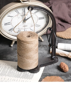 Close-up of vintage cast iron twine spool holder with rustic jute rope and black scissors