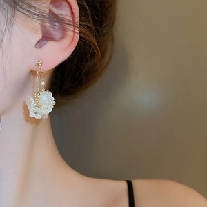 Detailansicht eleganter goldener Kettenohrringe mit weißen 3D-Blüten und Perlen