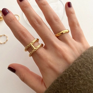 Close-up of elegant gold S925 sterling silver twist H-ring and simple smooth band