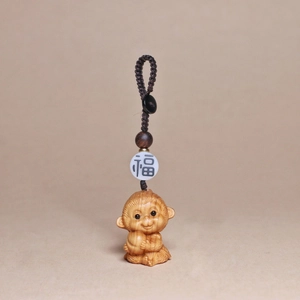 Detailed view of hand-carved wood monkey keychain with woven cord and luck bead