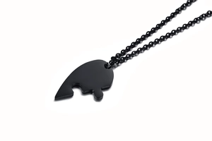 Detailed view of half-heart puzzle pendant in black titanium steel with matching chain