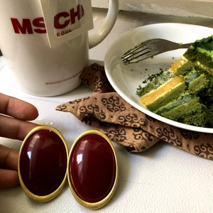 Detail of vintage oval earring with burgundy resin inlay and golden metal border frame