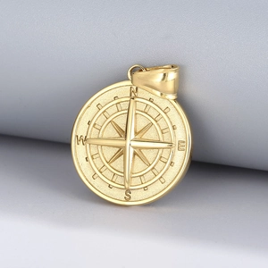 Detail view of a gold compass pendant with N E S W engraving in polished stainless steel