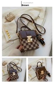 Detail of checkered brown crossbody bag with gold buckle and knit charm accessory