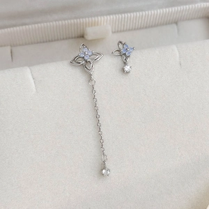 Detail of silver asymmetric earrings featuring floral zircon and long chain tassels