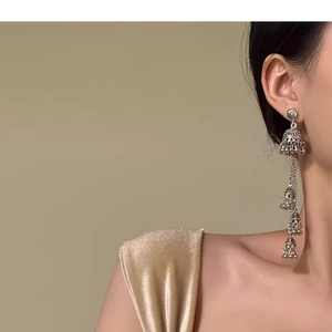 Close-up of vintage silver Jhumka earrings with tiered bell tassels on a model
