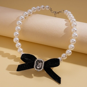 Close-up of pearl necklace with a black velvet bow and crystal center on display