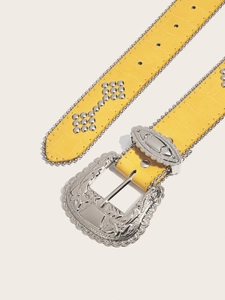 Detail of yellow crocodile pattern leather belt with studs and vintage western silver buckle