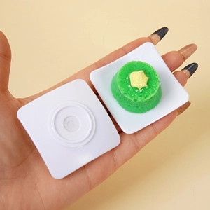 Mini torta verde e vassoi bianchi tenuti in mano per mostrare la scala della casa delle bambole