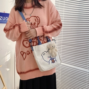 Detail view of a white canvas tote bag with a cute bear illustration and blue strap