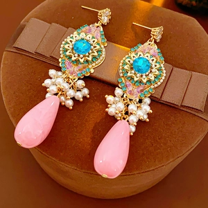 Détail de boucles d'oreilles vintage avec pierres bleues, papillon rose et perles