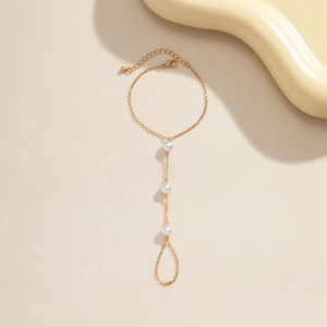 Detail of gold hand chain featuring three pearls and adjustable lobster clasp closure