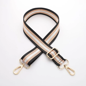 Detail of adjustable thick canvas bag strap with gold metal buckles and stripe pattern