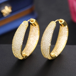 Macro view of gold hoop earrings with full pave cubic zirconia on black leather