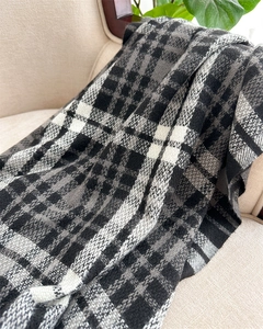 Detail of classic black and white plaid knit blanket scarf with warm textured fringe