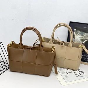 Woven leather tote bag in caramel and beige colors with wide weave texture and top handles