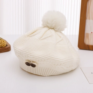 Detailed knit texture of cream-colored kids' beret with soft pompom and small bear patch