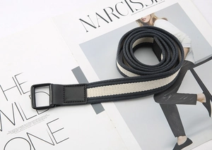 Detail of navy and beige striped canvas belt with double D-ring buckle on a magazine