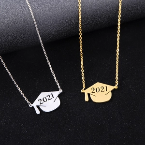 Macro detail of gold and silver graduation cap pendants with 2021 engraving on black background