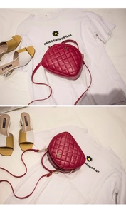 Detailed macro view of a red quilted PU leather crossbody bag with golden flower clasp