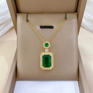 Close-up of gold titanium necklace with micro-pave emerald pendant in beige jewelry box