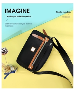Detail of lightweight black nylon crossbody bag with brown leather trim and metal logo