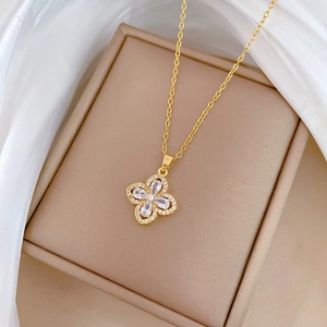 Macro detail of a gold clover necklace with zircon petals in an apricot jewelry box