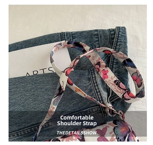 Detail of cream-white bag strap featuring colorful butterfly patterns and silver metal buckles