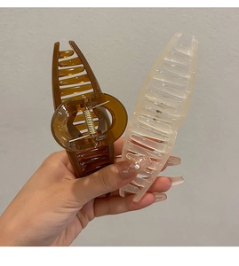 Close-up of large amber and cream hair claws held in hand showing sturdy spring mechanism