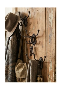 Detail of vintage cast iron coat hooks with rustic branch design on weathered wood