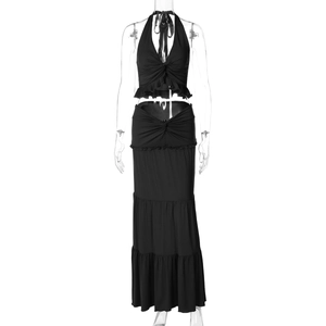 Detail of a black two-piece set featuring a halter neck top with knot and ruffled tiered skirt