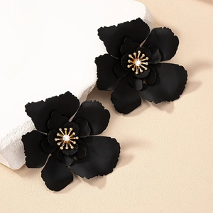 Macro detail of black matte petal earrings with gold stamen and white zircon stones