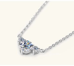 Macro view of sterling silver necklace with three-stone moissanite heart pendant