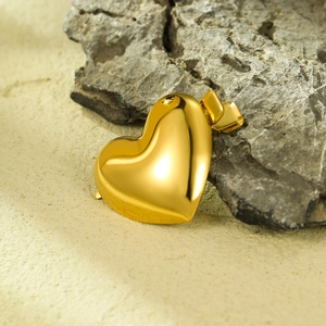 Elegant 18K gold-plated heart-shaped metal pendant on natural rock and sand background