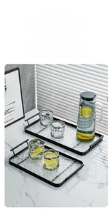 Close-up of a luxury water ripple glass serving tray with black metal handles and gold rims