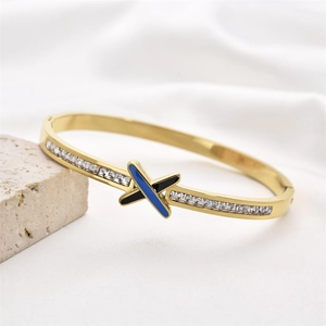 Gold stainless steel bangle with X-shaped blue black enamel and pavé zircon accents