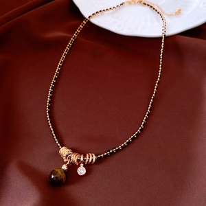 Detail of rose gold beaded necklace with tiger eye stone and zircon on silk fabric