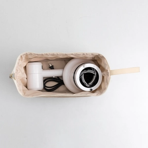 Top view of cream travel storage bag with wide compartment for hair dryer and accessories