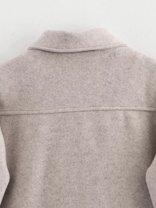 Detail of oatmeal tweed jacket neckline showing premium stitching and textured fabric