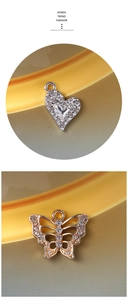 Macro detail of diamond-encrusted heart and butterfly alloy charms for DIY jewelry making