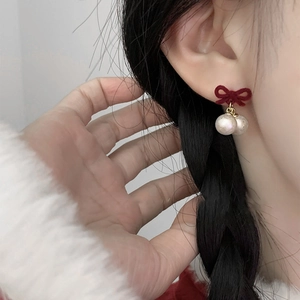Boucles d'oreilles nœud rouge plaqué or 14k avec perles blanches portées par un mannequin