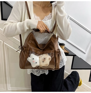 Detail of brown PU leather Itabag showing transparent window with plush doll keychains