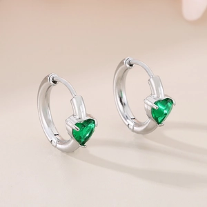 Macro view of heart-shaped emerald green zircon earrings with high-polish metal finish