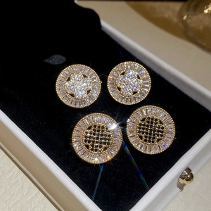 Macro detail of French retro gold plated round stud earrings with black and white zircon stones
