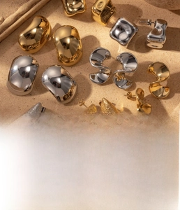 Detailed close-up of titanium steel earrings with vacuum plating on sandy texture