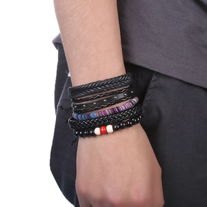 Détail d'un ensemble de 5 bracelets multicouches en cuir noir et perles sur un poignet homme