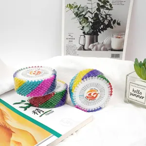 Colorful pearl head sewing pins set in a circular disc on a white decorative fabric