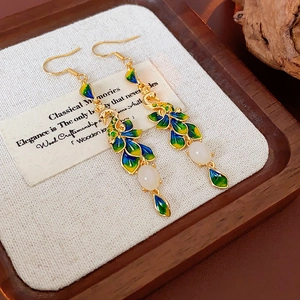 Dettaglio di orecchini a pavone placcati in oro 14K con smalto verde e gemma bianca